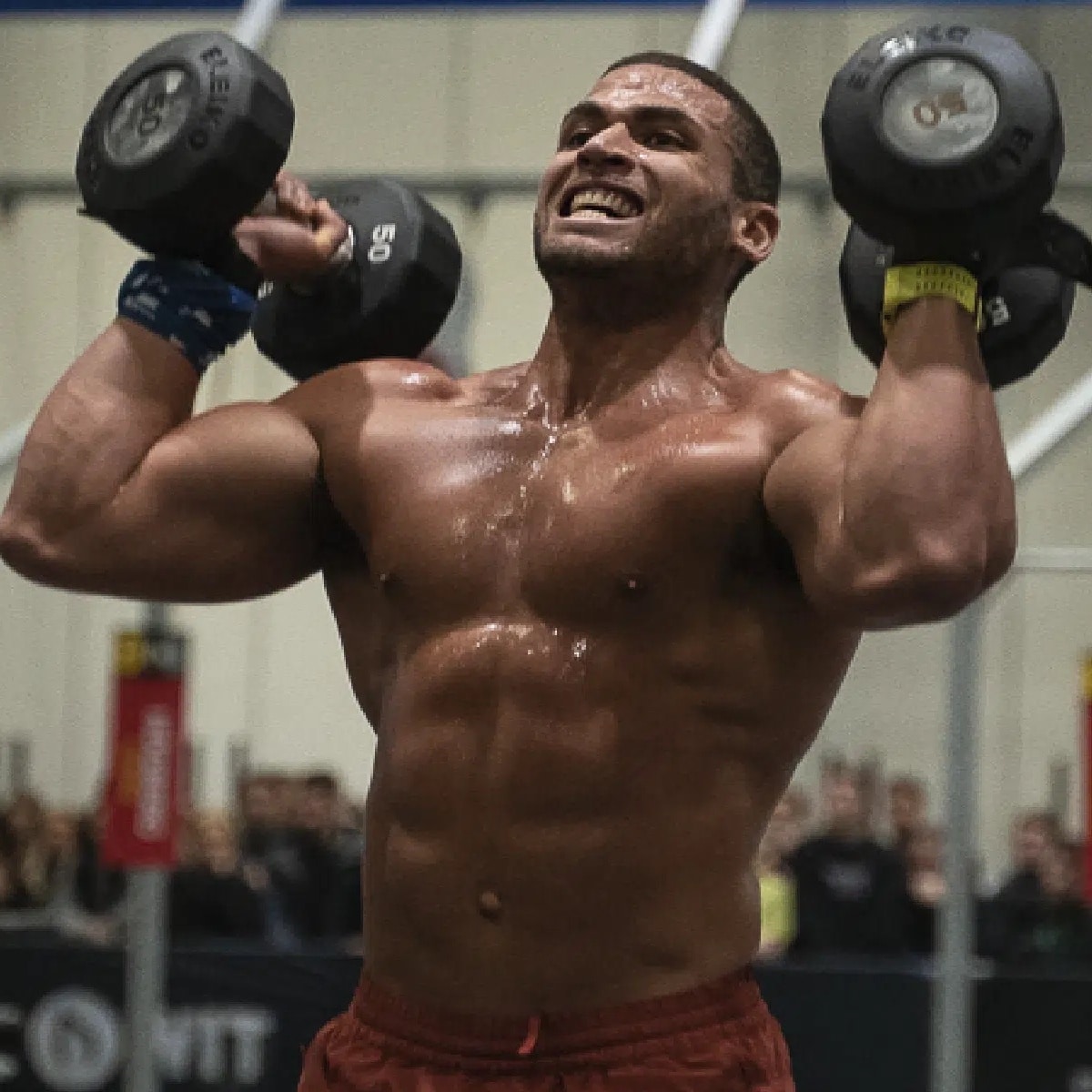 Muscular man lifting dumbbells, visibly exerting effort.