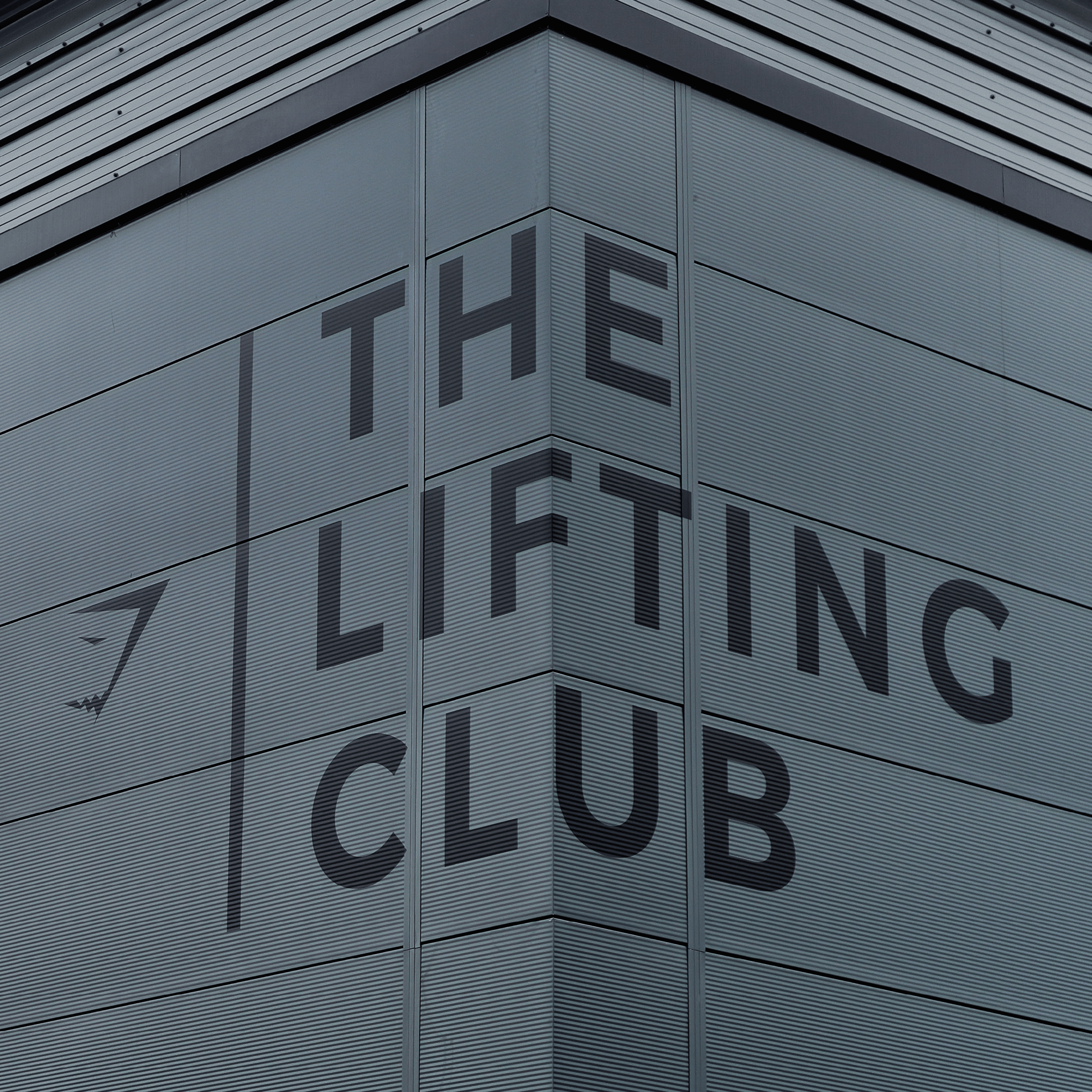 Corner of a modern building with "THE LIFTING CLUB" text on its facade.