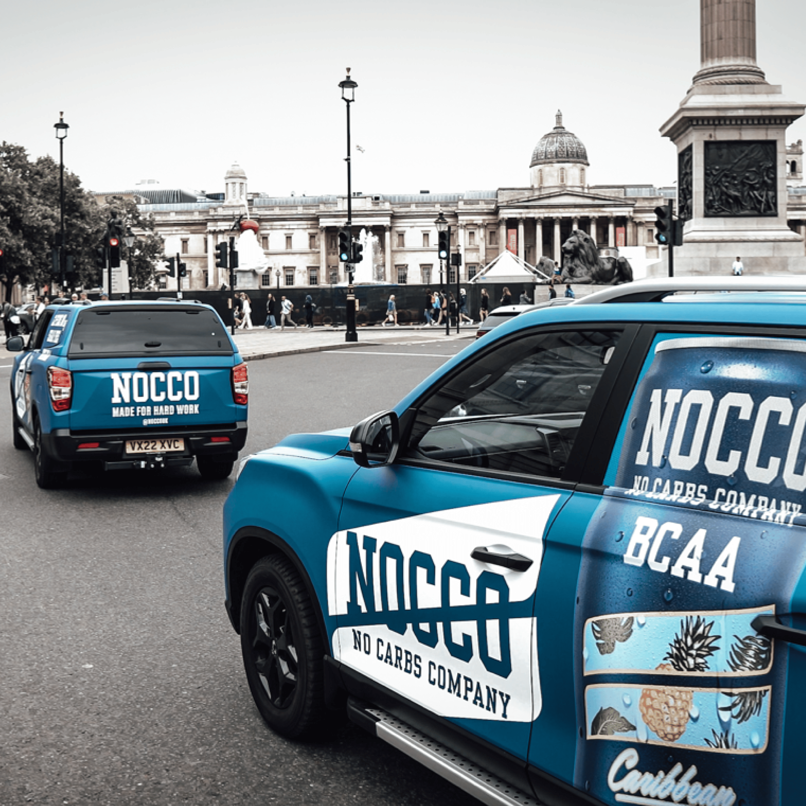 Two branded NOCCO vehicles in front of Trafalgar Square, London.