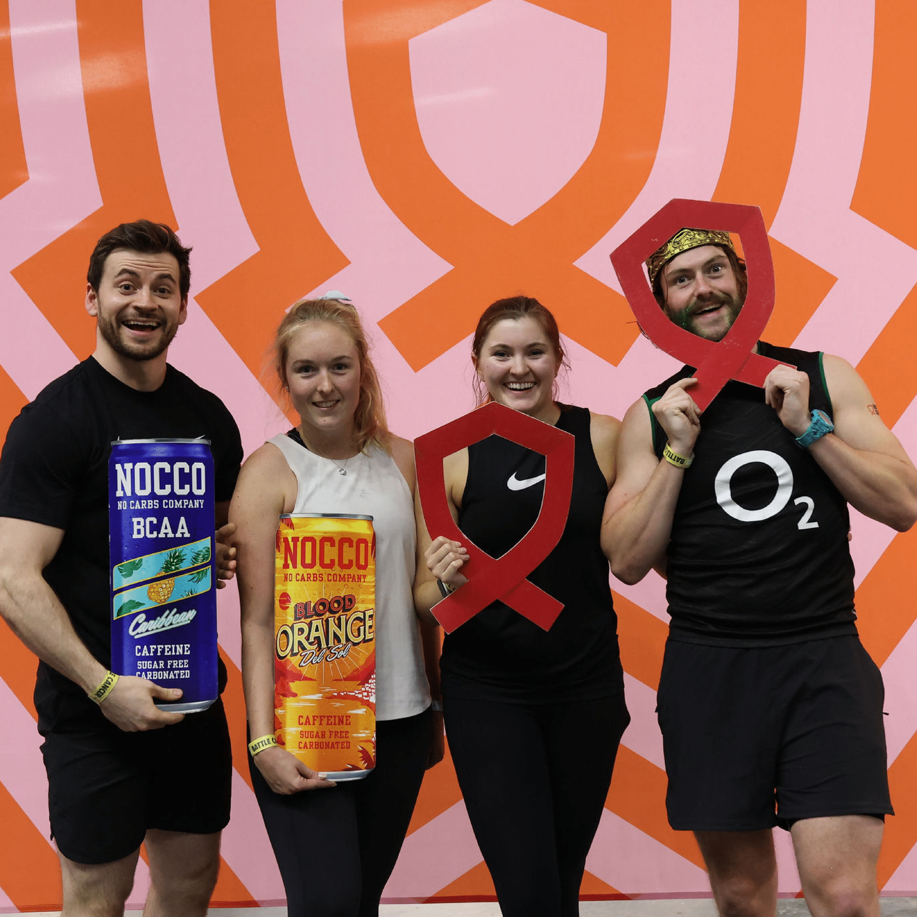 Four people posing with exercise props against a patterned orange background.